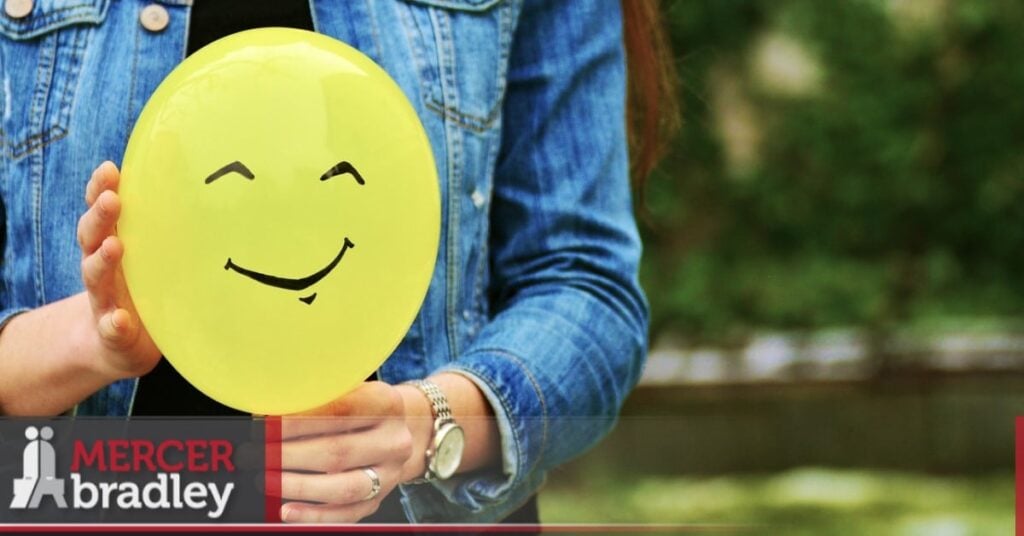 Person holding a happy face representing a positive first impression at a new job