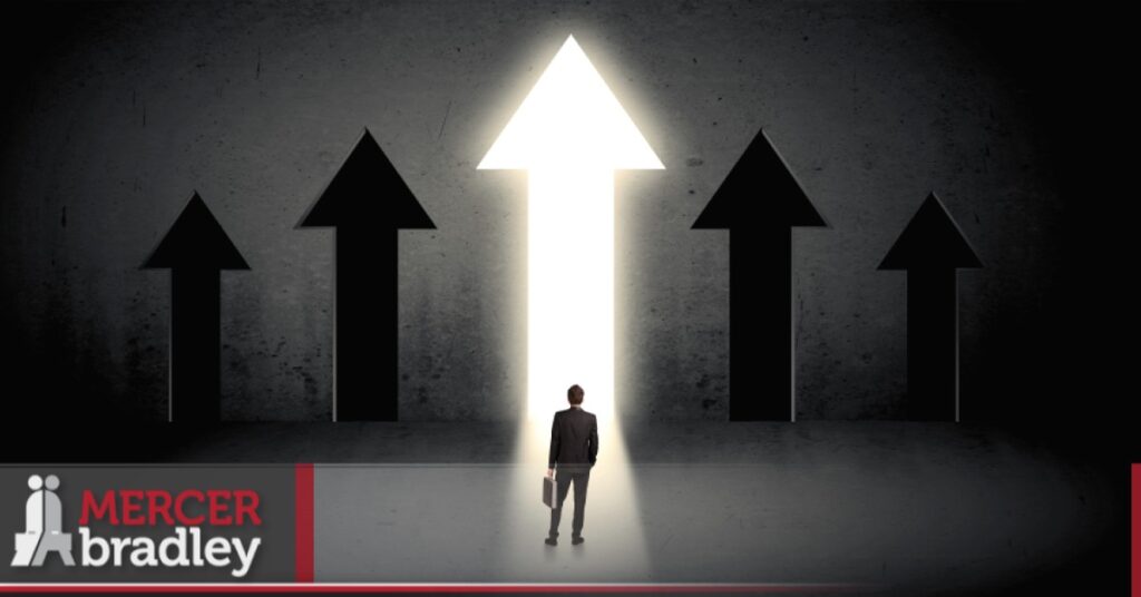 Business professional standing before bright upward arrow symbolizing streamlined hiring with Mercer Bradley in Winnipeg